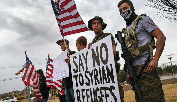 أحد المجموعات المسلحة في تكساس يحملون لافتة كتب عليها قل لا للاجئين السوريين