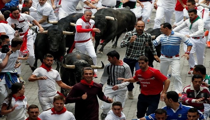 أشخاص يركضون أمام ثيران في مهرجان سان فيرمين في بامبلونا بشمال إسبانيا