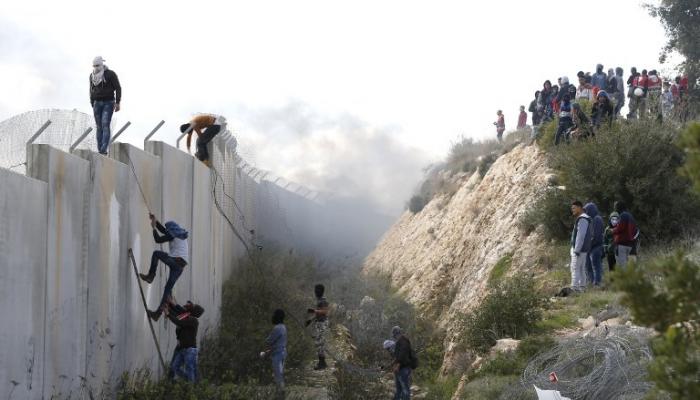 شبان فلسطينيون يتسلقون جدارا عازلا