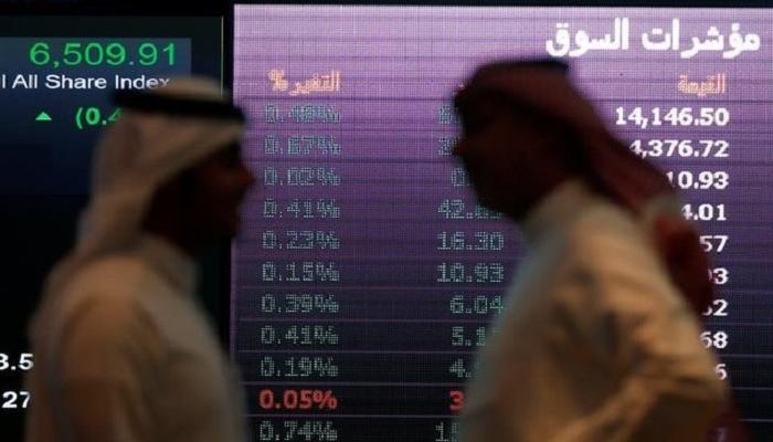 مستثمرون يتحدثون امام شاشة أسهم بورصة السعودية .رويترز