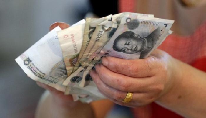 بائع يمسك عملات ورقية من اليوان في بكين
