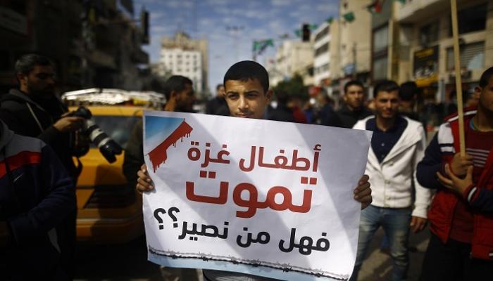 شاب فلسطيني يرفع لافته أثناء إضراب غزة