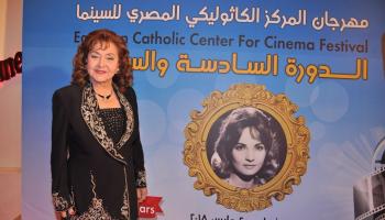 الفنانة ليلى طاهر إلى جوار لافتة المهرجان