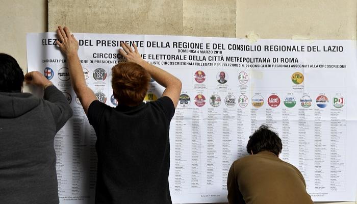 تعليق ملصقات انتخابية بأحد مراكز الاقتراع في إيطاليا - أ.ف.ب