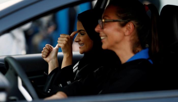 امرأة سعودية تبتسم وهي تجلس في سيارة أثناء تدريب على القيادة 