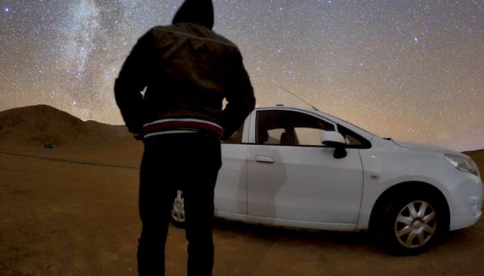 ظل الراصد يظهر على سيارته وفي الخلفية نجوم درب التبانة
