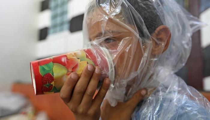 طفل سوري يجرب الكمامة البدائية للوقاية من هجوم كيميائي