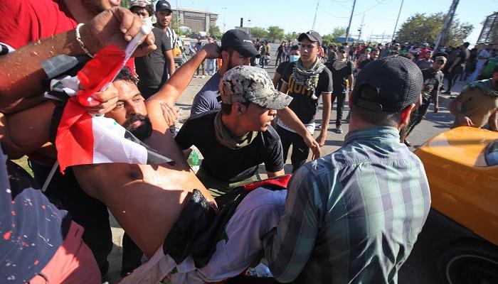 المتظاهرون يحملون أحد المصابين في العراق
