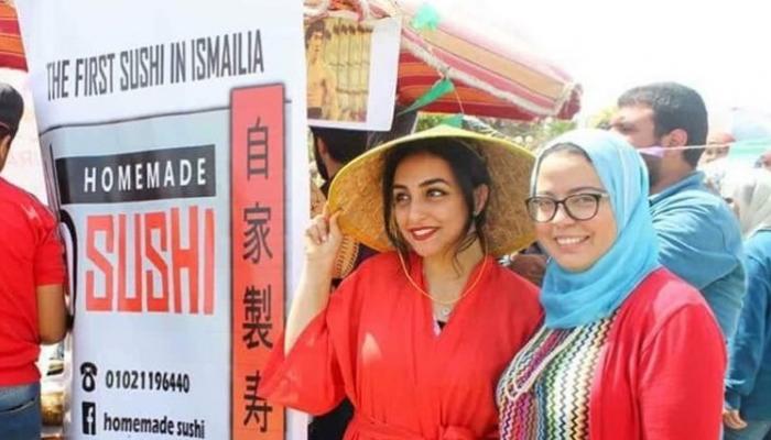 دينا عرفة (على اليمين) إلى جوار لافتة