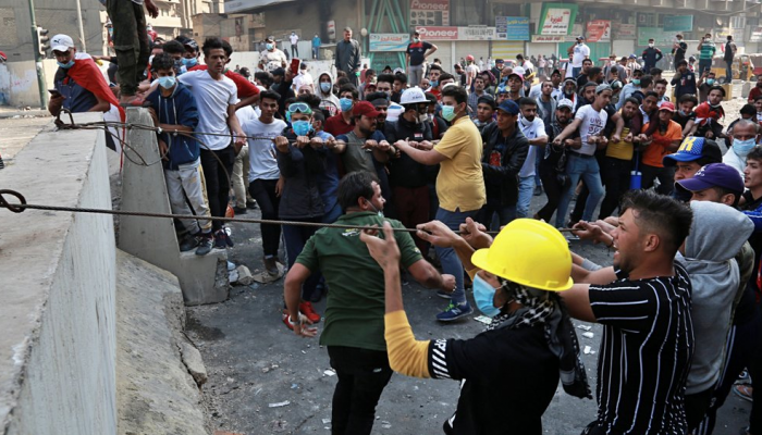 عراقيون يحاولون رفع أحد الحواجز في بغداد
