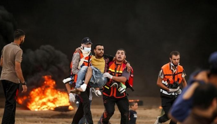 شاب فلسطيني محمولا بعد إصابته في مسيرات العودة بغزة- أرشيفية