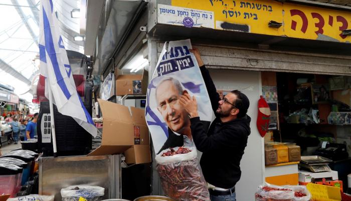 إسرائيلي يحمل ملصقا لحملة نتنياهو في الانتخابات