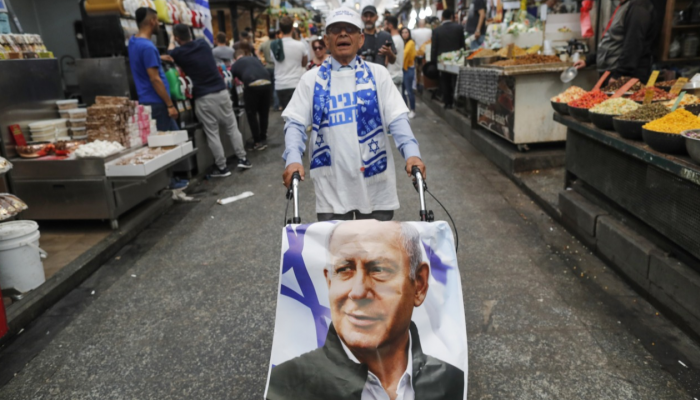 إسرائيلي يسير بملصق لنتنياهو  في أحد أسواق تل أبيب