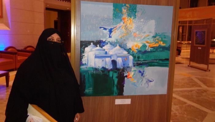 الرسامة الإماراتية منى الخاجة بجانب لوحتها "مسجد البدية"