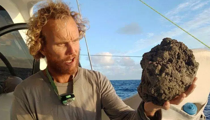 أحد البحارين وفي يده عينة من الأحجار البركانية