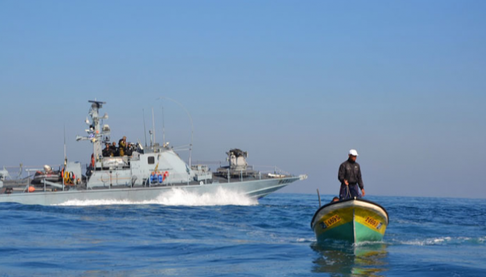 زورق للبحرية الإسرائيلية يمر بجوار قارب صيد في بحر غزة