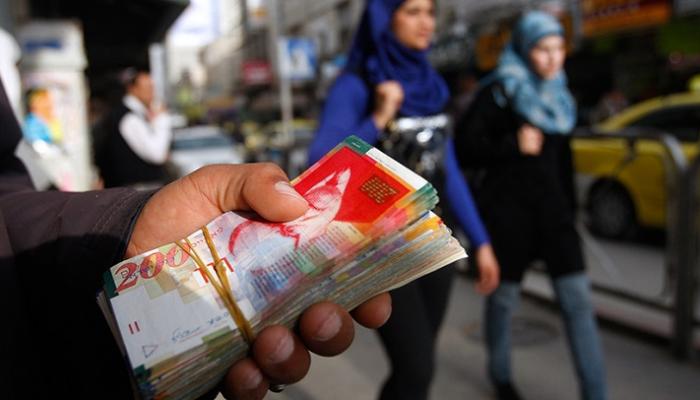 امرأة فلسطينية تمر أمام صراف في مدينة رام الله بالضفة الغربية
