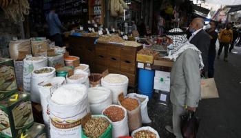 أردنيون يرتدون الكمامة أمام محل للعطارة