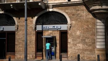 لبناني أمام ماكينة صراف آلي خارج فرع بنك -رويترز