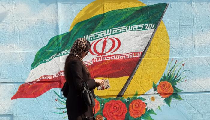 إيرانية تسير أمام جدارية علم