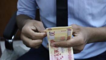 موظف بأحد مصارف ليبيا يحصي أوراقًا من فئة الـ20 دينارًا. (أرشيفية)ليبيا