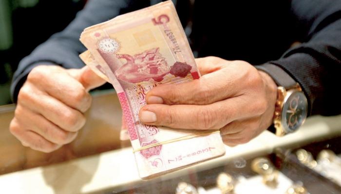 موظف بأحد مصارف ليبيا يحصي أوراقا من فئة الـ5 دينارات - أرشيفية
