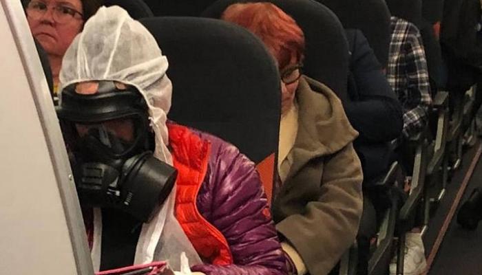 أحد ركاب طائرة قادمة من إيطاليا يرتدي سترة وقائية خوفا من كورونا