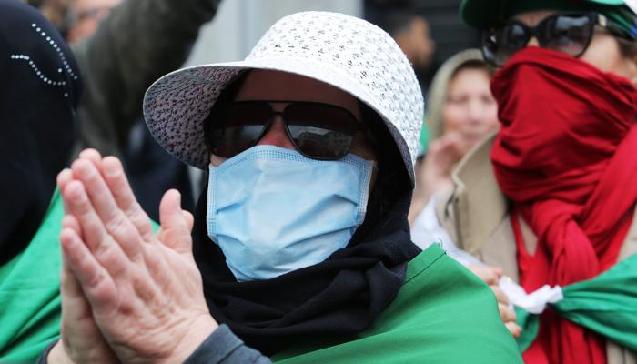جزائرية ترتدي الكمامة خلال مشاركتها بإحدى المظاهرات