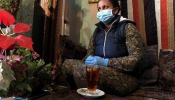 امرأة ترتدي قناعا وقفازات كإجراء احترازي لمكافحة انتشار فيروس كورونا في كيب تاون