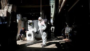 عامل يرتدي بذلة واقية يرش مطهرا بأحد أسواق مدينة ديار بكر