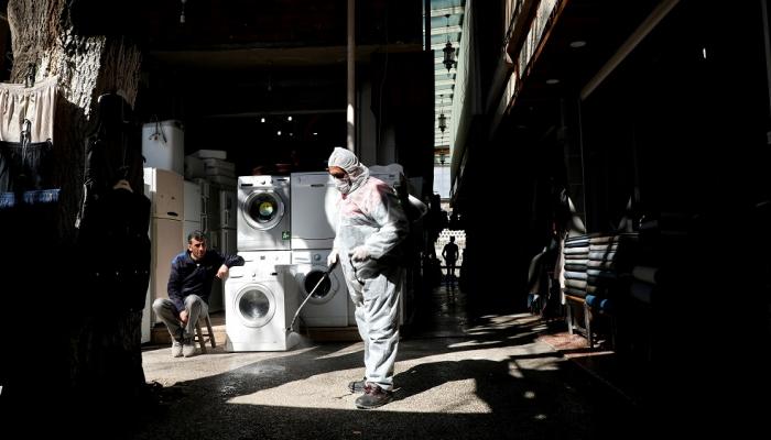 عامل يرتدي بذلة واقية يرش مطهرا بأحد أسواق مدينة ديار بكر