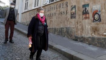 فرنسيان يرتديان الكمامة في أحد شوارع باريس