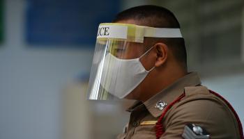 شرطي يرتدي قناعا وكمامة لوقايته من كورونا بتايلاند