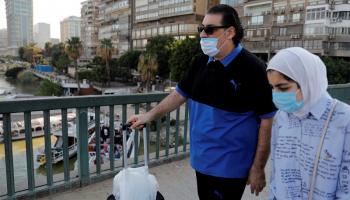مصريان يرتديان كمامة الوقاية يسيران على جسر فوق نهر النيل بالقاهرة
