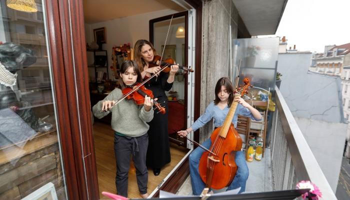 عازفة فرنسية وابنتاها يعزفن الموسيقى من شرفة المنزل التزاما بالحجر