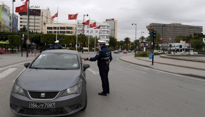 شرطي تونسي يفحص أوراق سيارة للتأكد من تطبيق حظر التجول لاحتواء فيروس كورونا