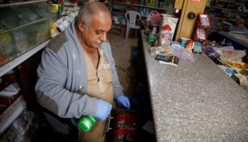 فلسطيني يرش المطهرات في متجره بالضفة الغربية