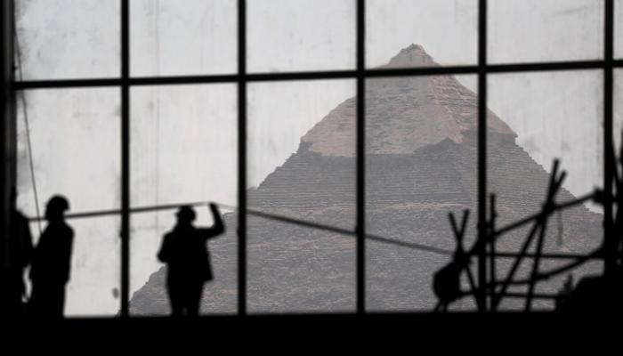 عمال البناء في موقع المتحف المصري الكبير أمام أهرامات الجيزة