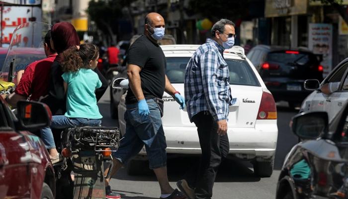 مصريون يرتدون الكمامات في أحد شوارع القاهرة - رويترز