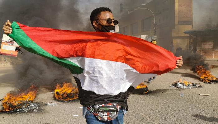 صورة أرشيفية لمتظاهر سوداني يمسك بعلم بلاده