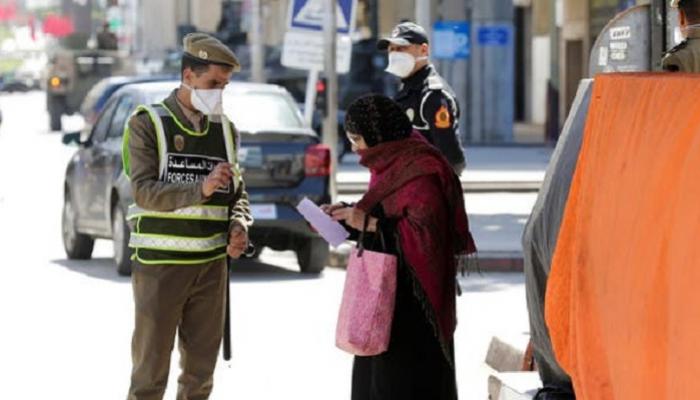 شرطي مغربي يرتدي الكمامة يساعد عجوزا في شوارع الرباط