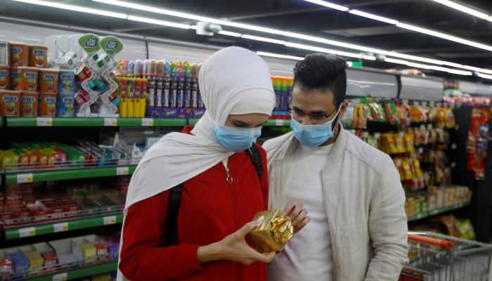 عراقي وزوجته يرتديان الكمامة داخل أحد المحلات في بغداد
