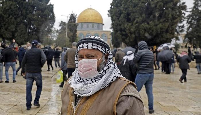 عجوز يرتدي الكمامة أمام مسجد قبة الصخرة بفلسطين