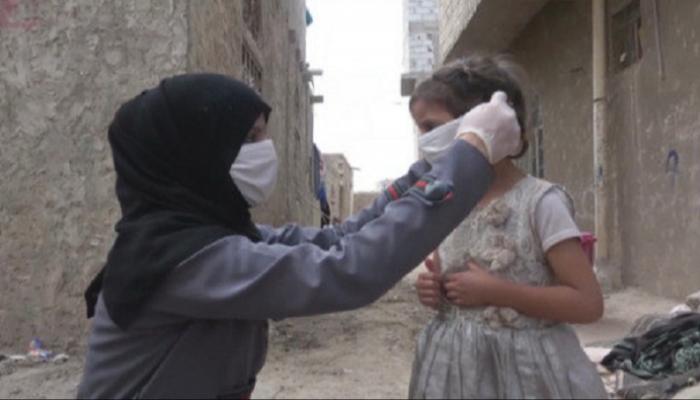 أمة يمنية تساعد ابنتها على ارتداء القناع الواقي