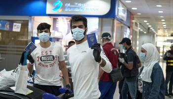 كويتيان يلوحان بجواز سفر بلادهما عقب الوصول قادمين من الأردن