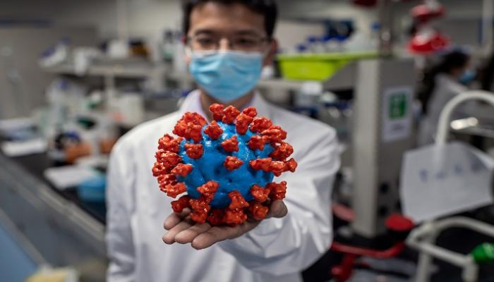 يعرض أحد المهندسين نموذجًا بلاستيكيًا للفيروس في مختبر ببكين - أ.ف.ب