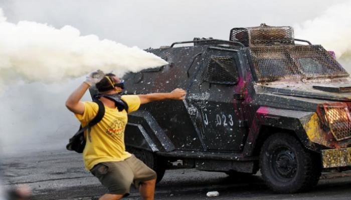 متظاهر يقذف سيارة للشرطة خلال مواجهات سابقة في تشيلي - أرشيفية