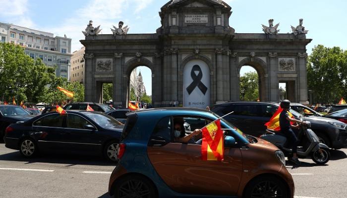 متظاهرون يحملون أعلام إسبانيا ضد تعامل الحكومة مع جائحة كورونا -رويترز