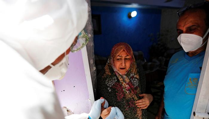 أخذ عينات دم من امرأة أثناء اختبار الإصابة بمرض فيروس كورونا في العراق