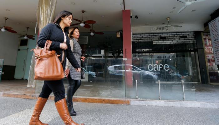 لبنانيتان تسيران إلى جوار مقهى مغلق في بيروت